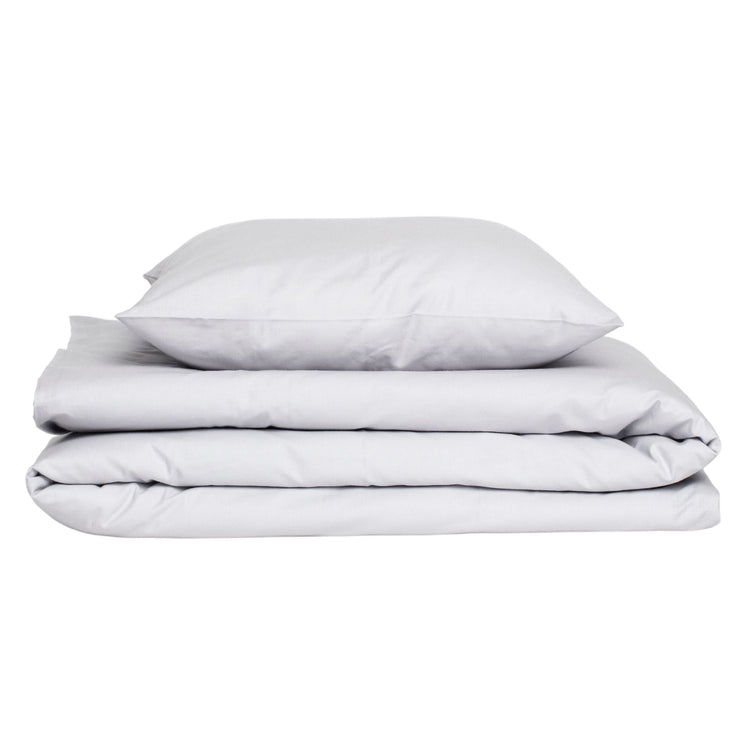 Premium white caravan bedding set featuring a folded duvet cover and plush pillows in crisp cotton, arranged in a stack